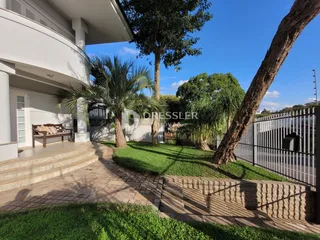 Vista da fachada de uma residência com jardim e palmeiras.