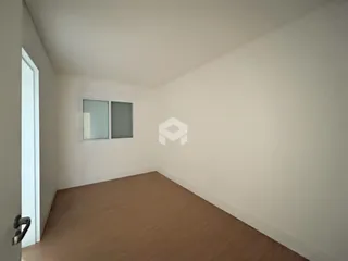 Vista interna de um cômodo com paredes brancas e piso de carpete.