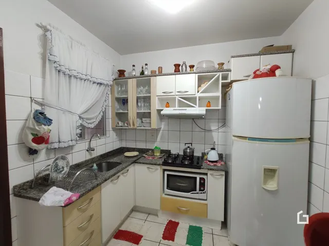Cozinha com armários brancos e revestimento de cerâmica nas paredes.