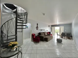 Sala de estar com escadaria e área de jantar em um imóvel no Brasil.