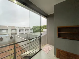 Vista de uma varanda com grade de vidro e vista para casas vizinhas em Lajeado.