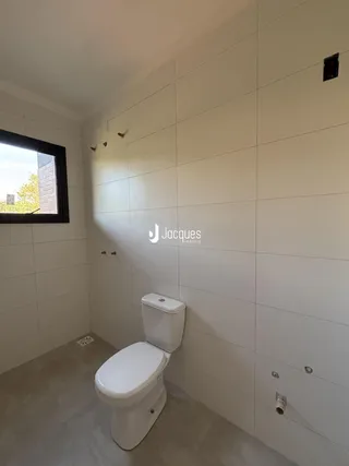 Foto de um banheiro com paredes revestidas de azulejos brancos.
