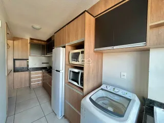 Vista da cozinha com armários de madeira e eletrodomésticos brancos.