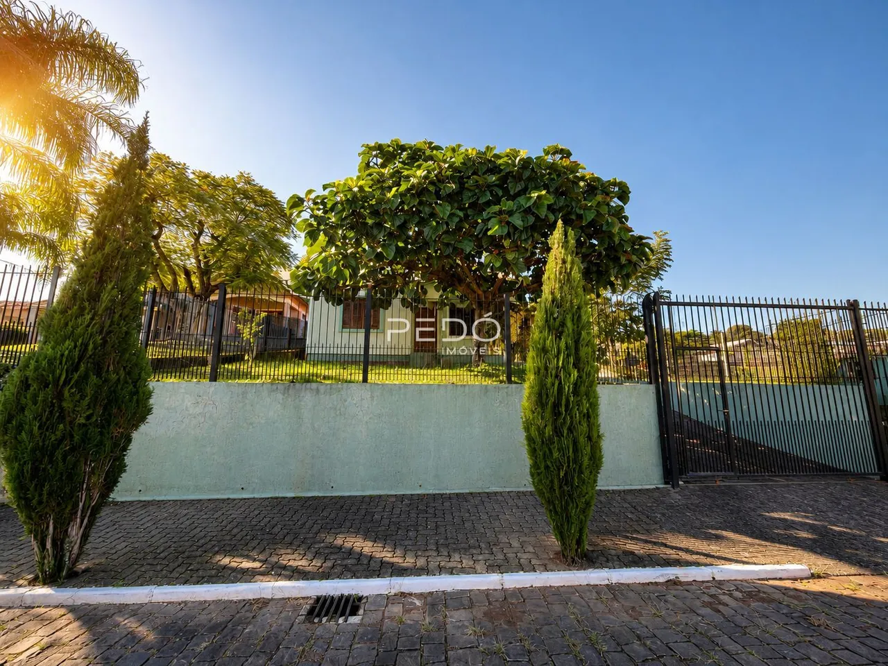 Vista externa de uma propriedade com muro e cerca de ferro.