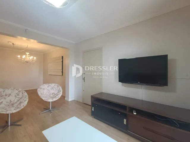Sala de estar com piso de madeira e televisão na parede.
