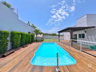 Piscina externa com deck de madeira ao lado de uma parede branca.