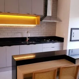 Foto de uma cozinha com armários brancos e bancadas escuras.