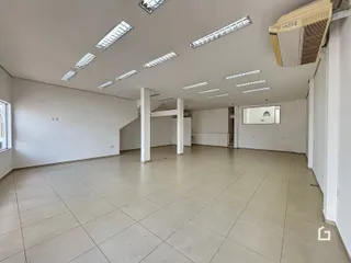 Imagem de um ambiente interno amplo com piso de cerâmica e teto com iluminação em painéis.
