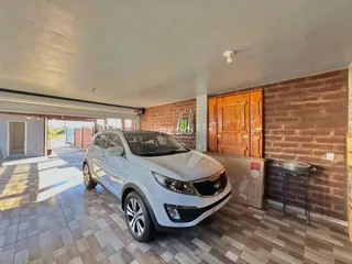 Interior de uma sala com parede de tijolos aparentes e porta de madeira.