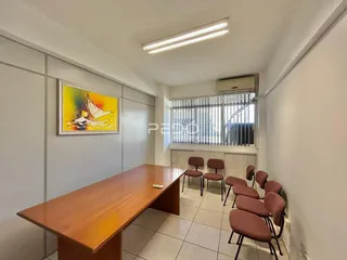 Ambiente interno de uma sala de jantar com mesa de madeira e cadeiras.