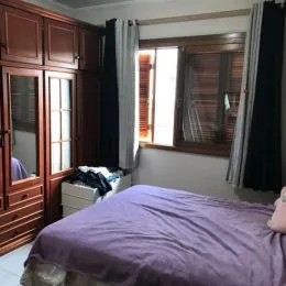 Quarto com cabeceira de madeira e cama coberta.