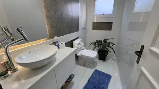 Banheiro moderno com pia e vaso sanitário em cerâmica branca.