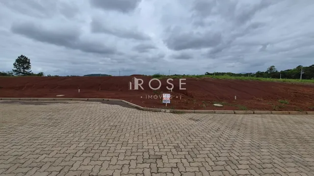 A foto mostra uma área externa de terreno com pavimento e terra avermelhada.