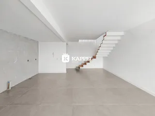 Vista de um ambiente amplo com piso claro e escadaria moderna.