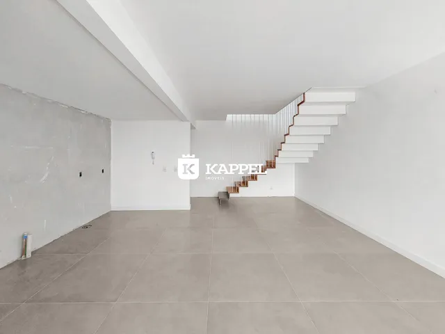 Vista de um ambiente amplo com piso claro e escadaria moderna.