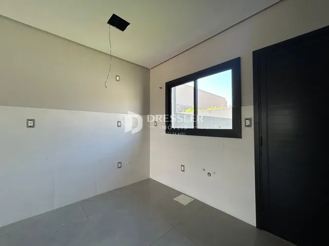 Interior de uma sala com paredes brancas e piso cinza claro.
