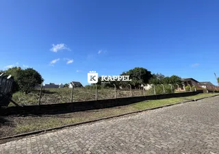 Vista externa de uma propriedade com cerca e vegetação ao fundo.