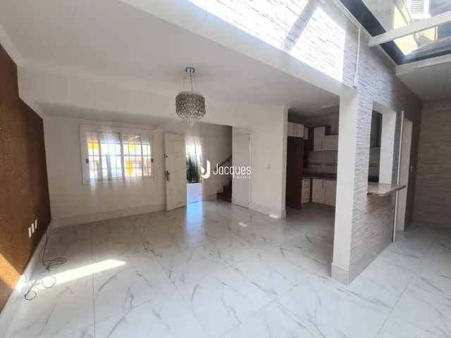 Sala de estar com piso de mármore branco e grandes janelas.