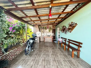 Uma área coberta com piso de madeira e vegetação exuberante é visível na propriedade.