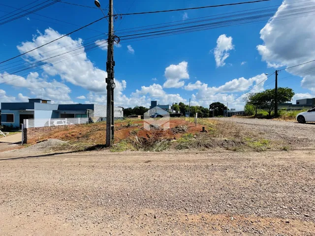 Foto de uma área de terreno com vegetação e estruturas ao fundo.
