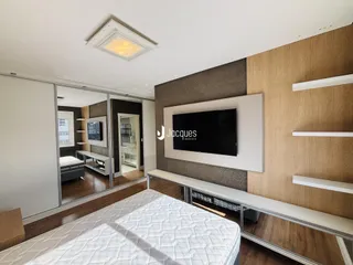 Quarto moderno com cama e painel de TV em sala de estar.