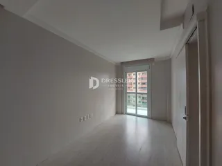 Vista interna de um cômodo longo com paredes brancas e piso claro.