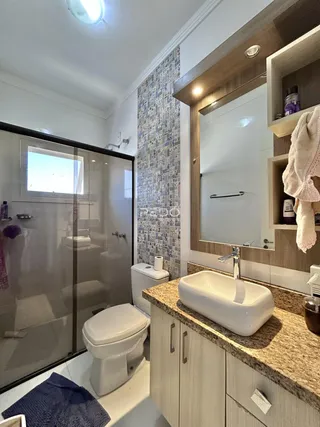 Banheiro com box de vidro e revestimento decorativo.