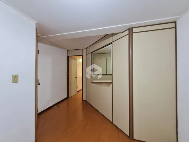 Um corredor interno com piso de madeira e paredes brancas.