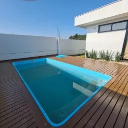 Foto da piscina externa com deck de madeira em uma propriedade.