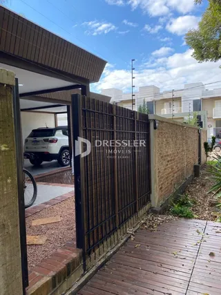 Fachada de uma propriedade com cerca de metal e parede de tijolos.