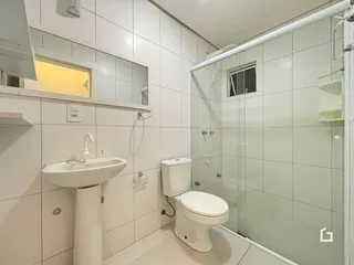 Foto de um banheiro com box de vidro e revestimento branco.