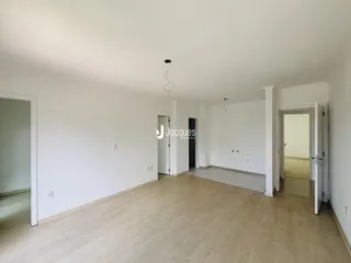 Ambiente interno de uma sala ampla com piso de madeira clara.