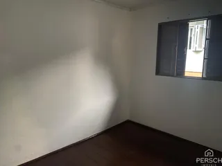 Ambiente interno com piso de madeira e parede branca.