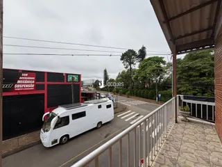 Vista externa de uma rua com um caminhão estacionado e uma cerca de metal.