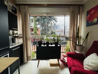 Sala de estar com móveis escuros e vista para o exterior.