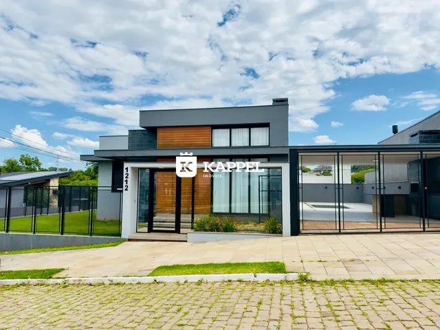 Fachada moderna de uma residência em Lajeado, Brasil, com revestimento cinza e detalhes em madeira.