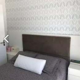 Foto de uma cama com cabeceira cinza.