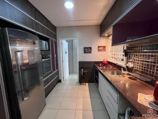 Foto interna de uma cozinha com armários escuros e bancada de granito.