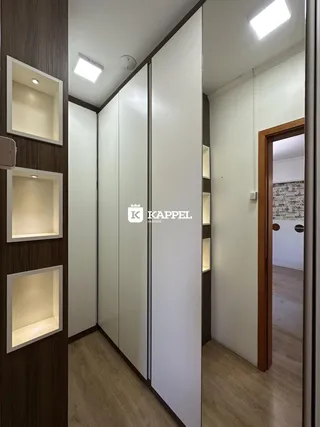 Hall de entrada com painéis de madeira e armários brancos.