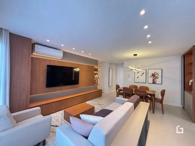 Sala de estar moderna com sofá e área de jantar em um apartamento.