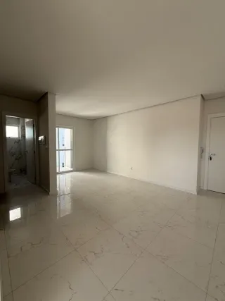 Sala ampla com piso de porcelanato claro e paredes brancas.