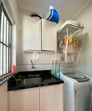 Vista da cozinha com armários brancos e bancada escura.