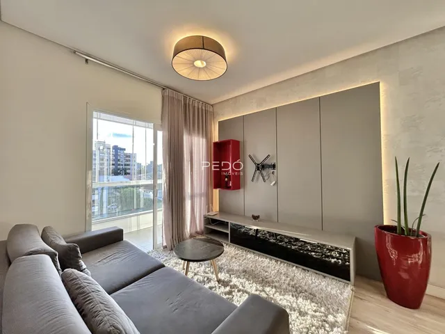 Sala de estar com sofá e grandes janelas de vidro.
