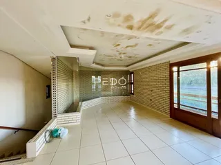 A foto mostra um corredor com piso de cerâmica e parede de tijolos.