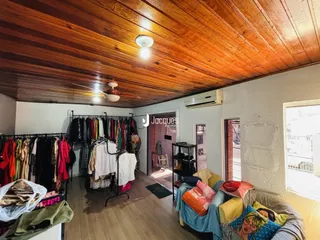Interior de uma sala com teto de madeira e roupas penduradas.