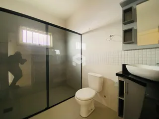 Foto de um banheiro com revestimento cerâmico e divisória de vidro.