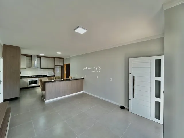Ambiente de sala e cozinha moderna com piso claro.