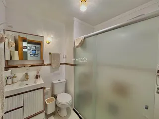 Foto de um banheiro com box de vidro e louças brancas.