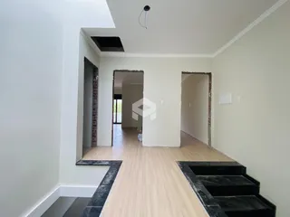 Hall de entrada com paredes brancas e piso de madeira clara.