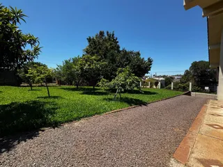 Vista externa do terreno com gramado e caminho de cascalho.